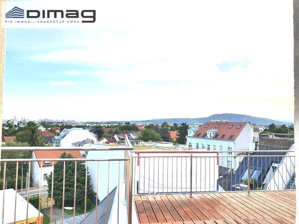 Panoramablick von der Dachterrasse über die Stadt und die umliegende Landschaft mit Hügeln am Horizont.