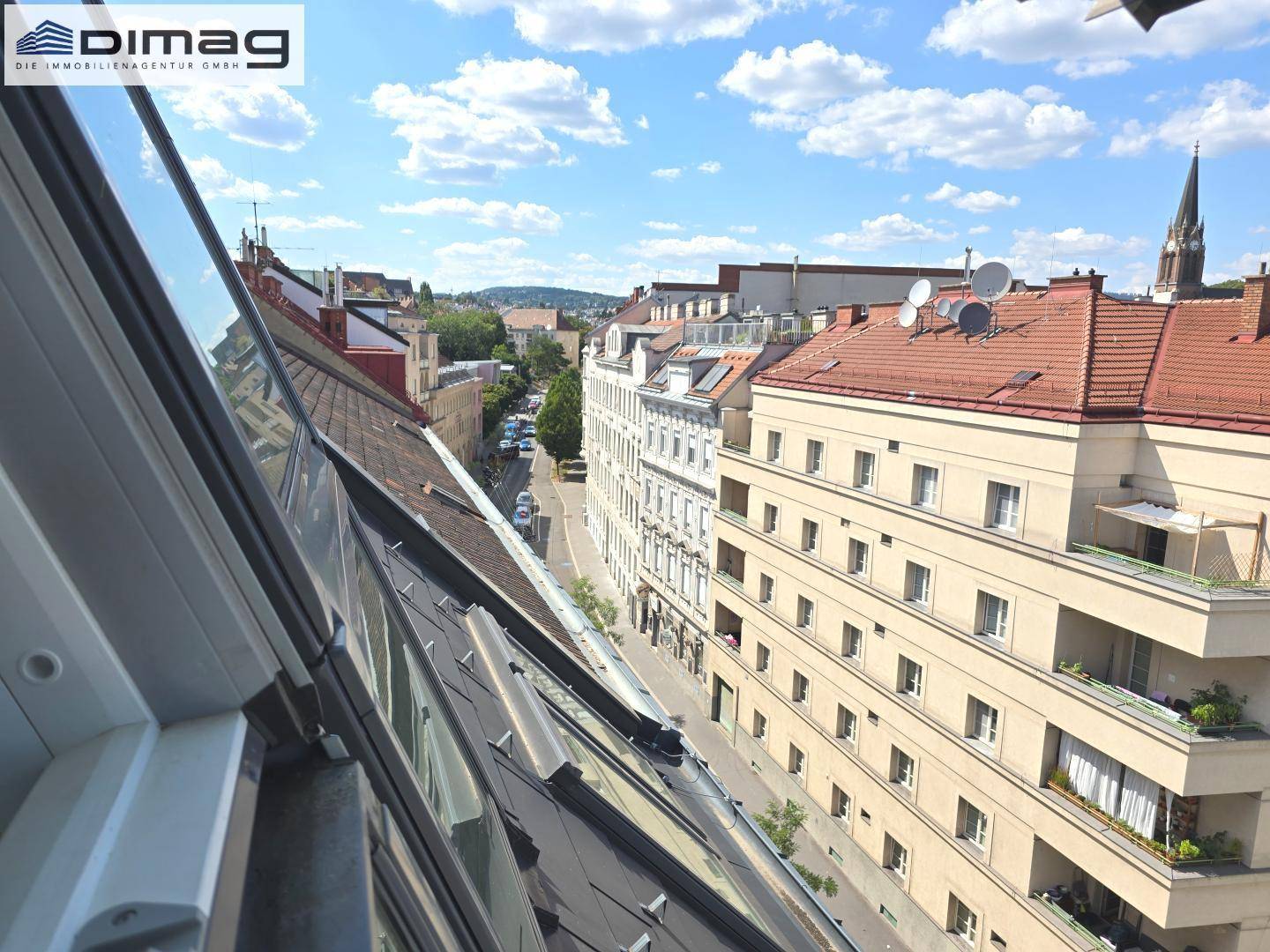 Panoramablick über die Dächer der Stadt mit historischen Gebäuden und einer Kirche im Hintergrund.