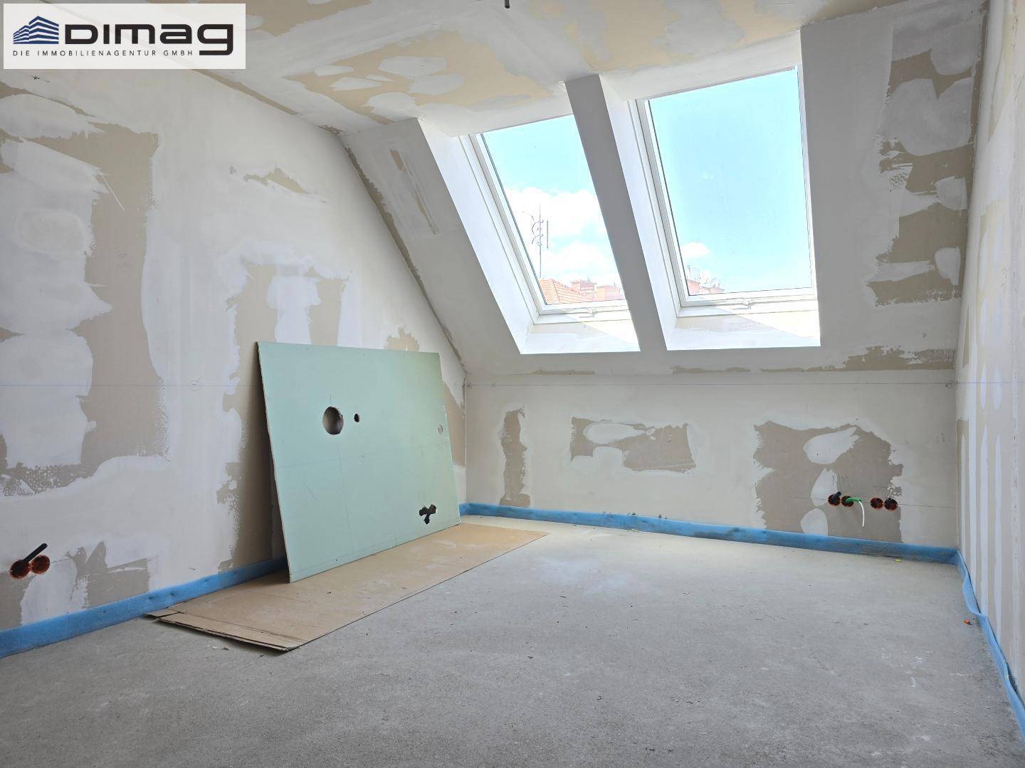 Rohbau-Zimmer mit Dachschräge und einem Dachfenster, bereit für den Innenausbau.