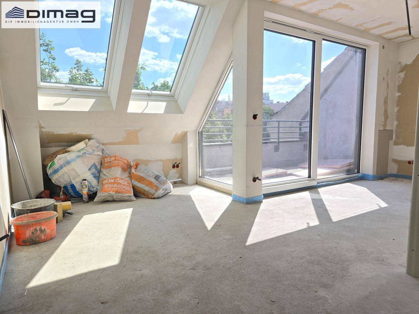 Unfertiger Raum mit Schiebetür zur Terrasse und Dachfenstern, ideal für sonnige Tage.