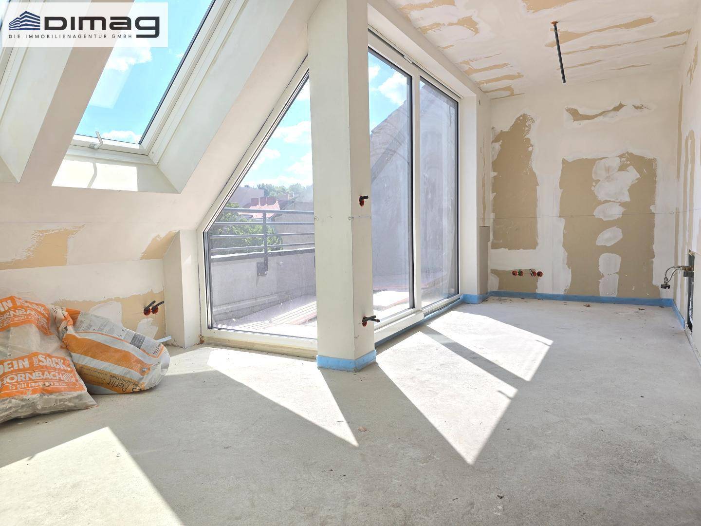 Rohbau-Raum mit Zugang zu einer Terrasse und einem Dachfenster, bietet viel Tageslicht.