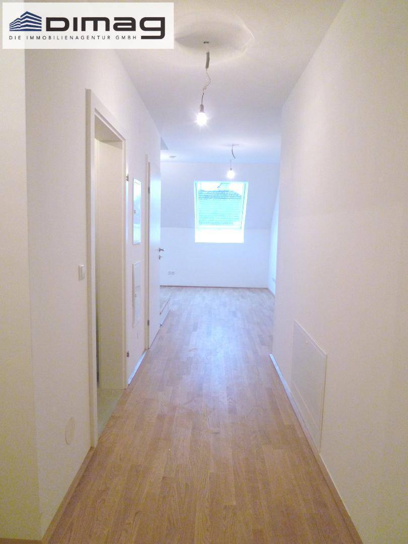 Langer, heller Flur mit Parkettboden und einem Dachfenster am Ende des Ganges.