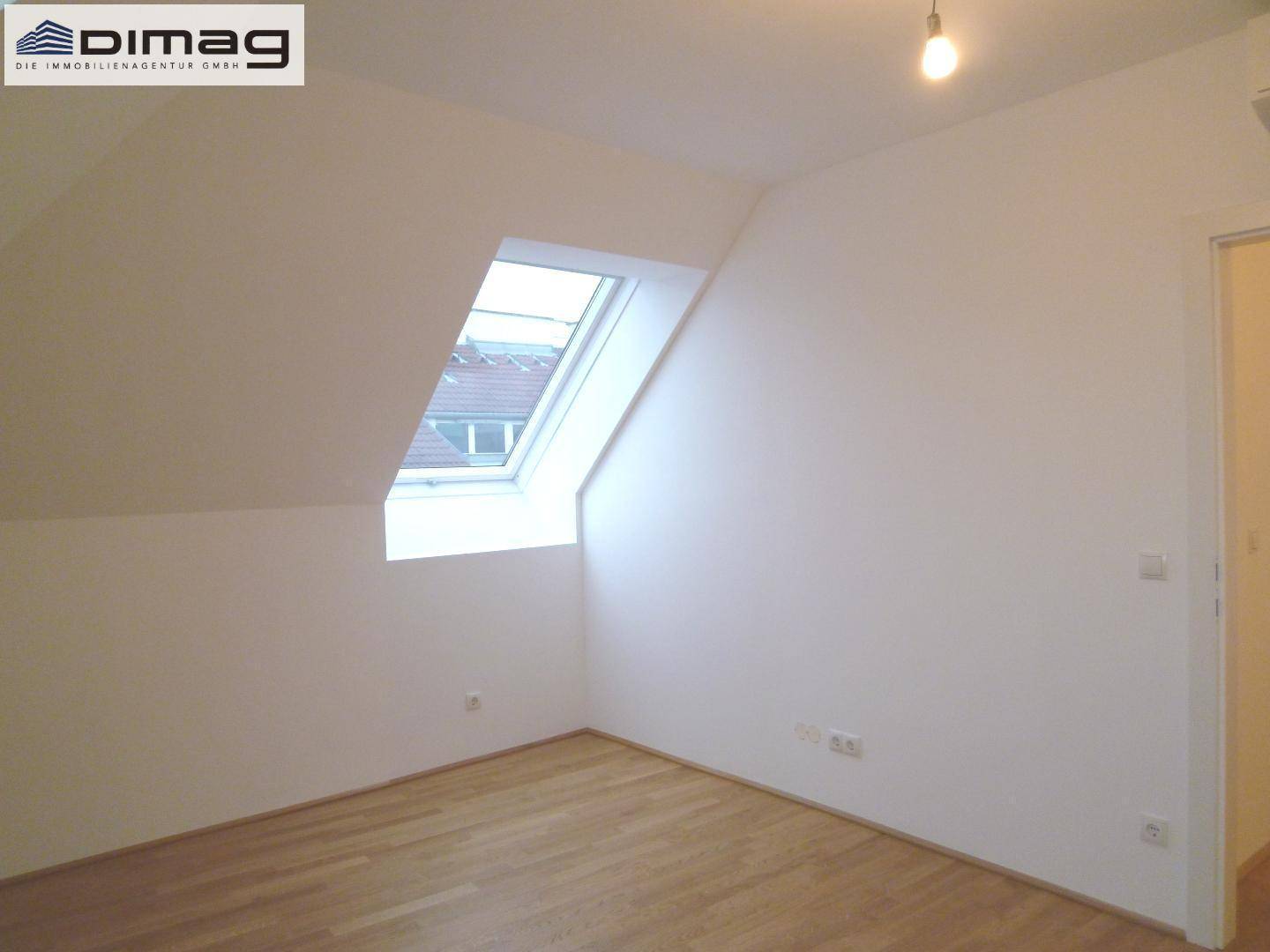 Kleineres Dachgeschosszimmer mit einem Dachfenster und hellem Parkettboden.