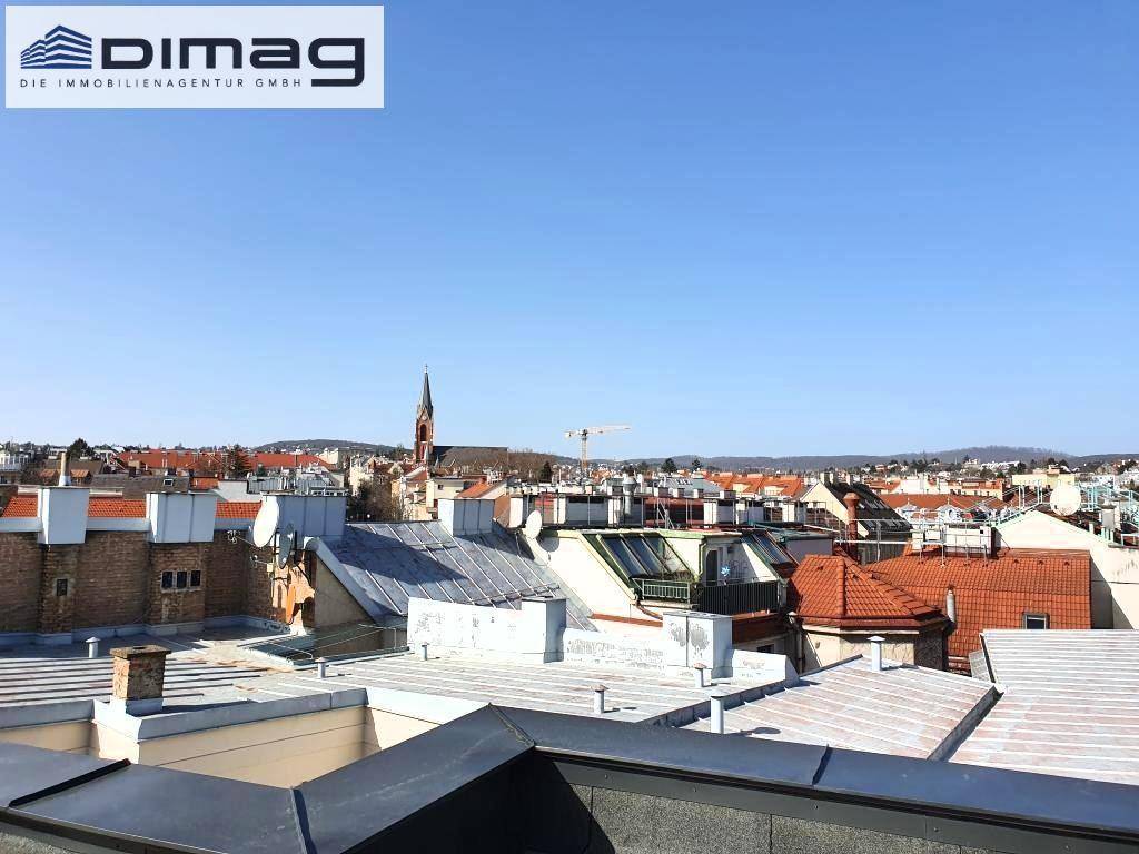 Sonniger Ausblick über die Dächerlandschaft der Stadt mit historischer Kirchturmspitze.