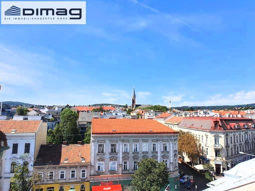 Weitblick über die städtische Bebauung mit roten Dächern und einer Kirchturmspitze.