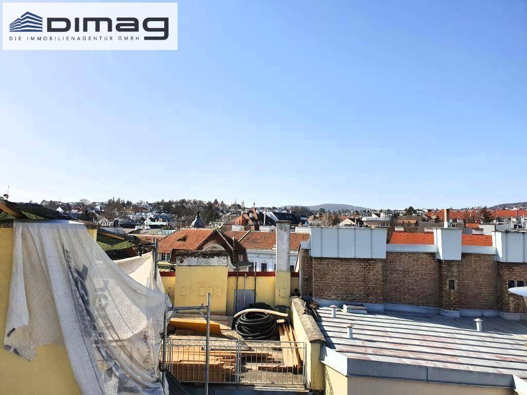 Blick über die Dächer mit angrenzenden Gebäuden und Bauelementen unter klarem Himmel.