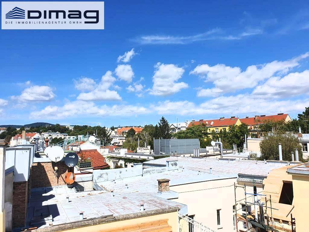 Blick über die umliegenden Dächer mit verschiedenen Gebäudetypen unter blauem Himmel.