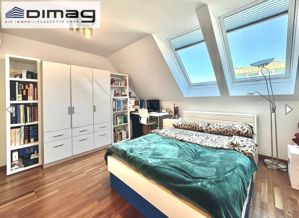 Helles Schlafzimmer mit Holzboden, Dachfenstern und integriertem Arbeitsbereich.