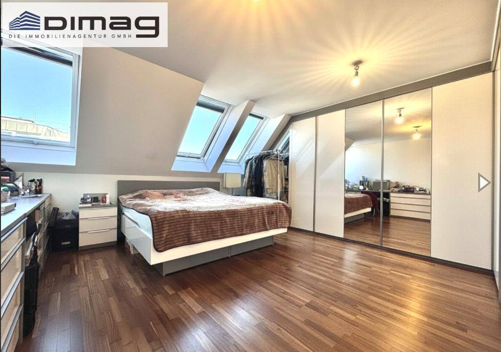 Schlafzimmer mit Holzboden, Dachschrägen und Spiegelschränken für viel Stauraum.