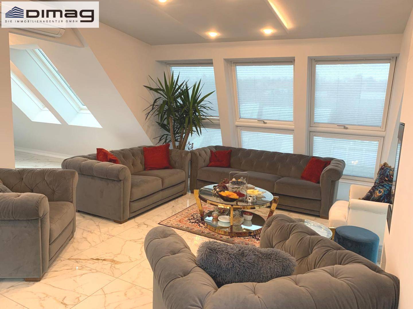 Gemütliches Wohnzimmer mit Dachfenstern, eleganten Sofas und einem modernen Kamin.