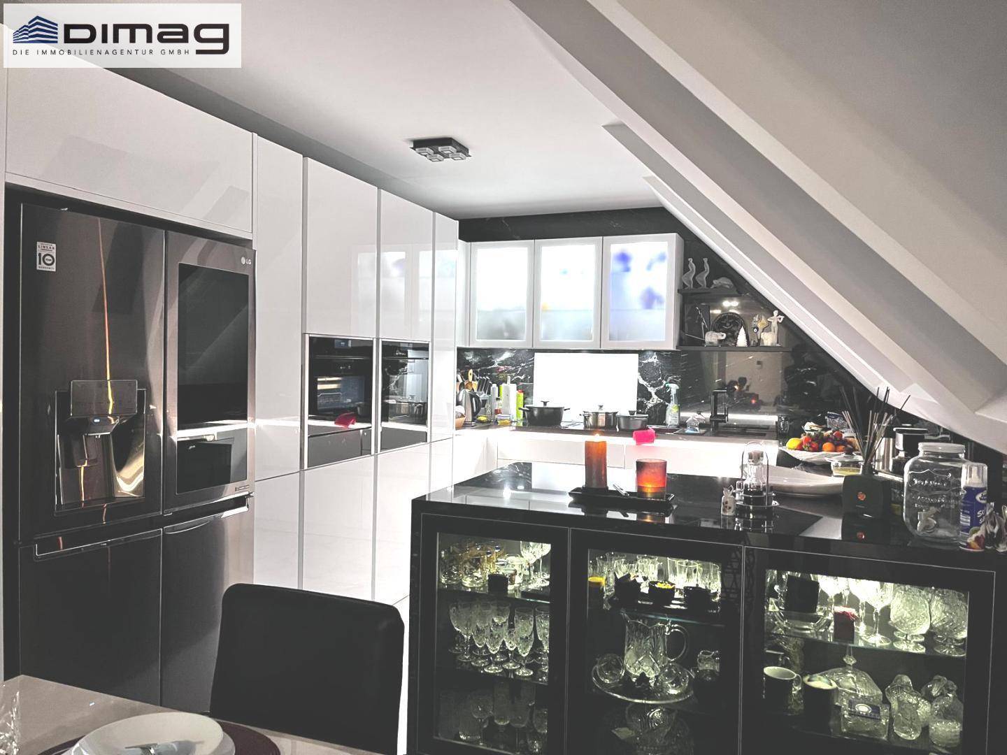 Hochwertige Küche mit großem Kühlschrank, weißen Schränken und schwarzer Kücheninsel.