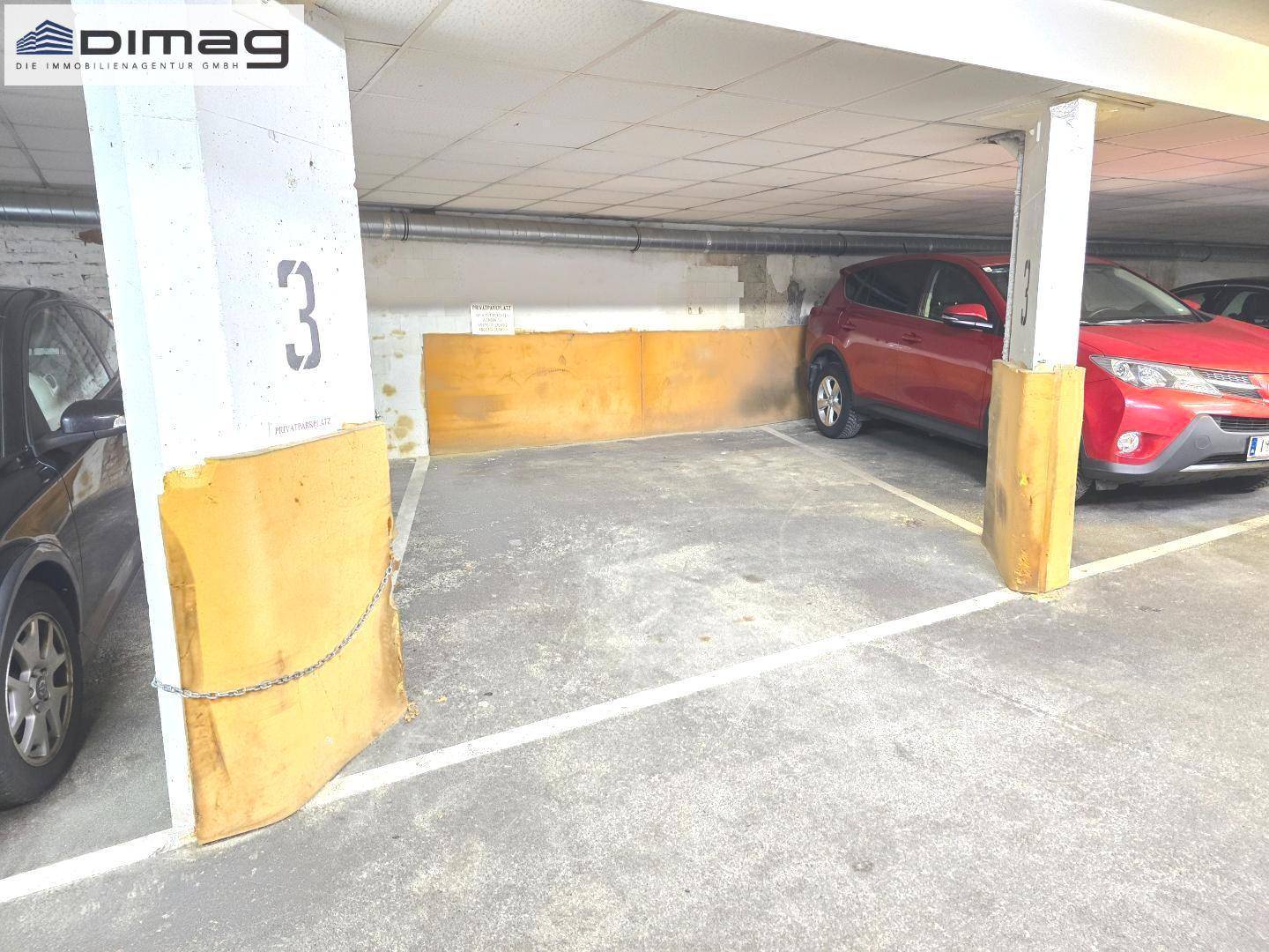 Geräumiger Tiefgaragenstellplatz, umgeben von stabilen Betonpfeilern und einer Ziegelwand.