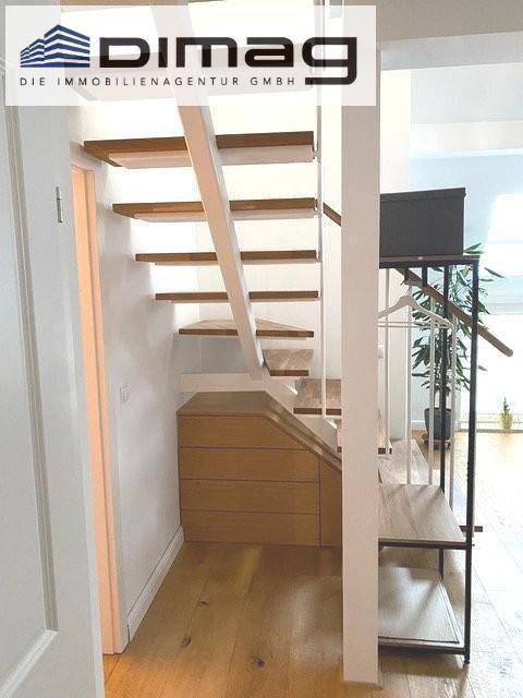 Elegante Holztreppe mit integrierten Schubladen für zusätzlichen Stauraum im Flurbereich.