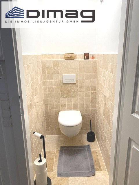 Gäste-WC mit beigefarbenen Fliesen und wandhängendem WC für ein modernes Erscheinungsbild.