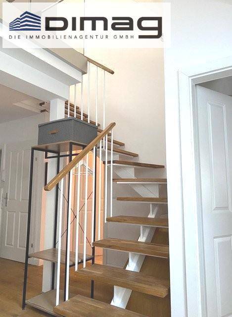 Moderne Holztreppe mit schlanken weißen Geländerstäben und elegantem Holzhandlauf.