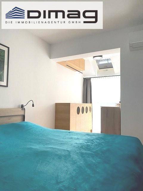 Gemütliches Schlafzimmer mit Holzelementen, Klimaanlage und natürlichem Licht durch ein Dachfenster.