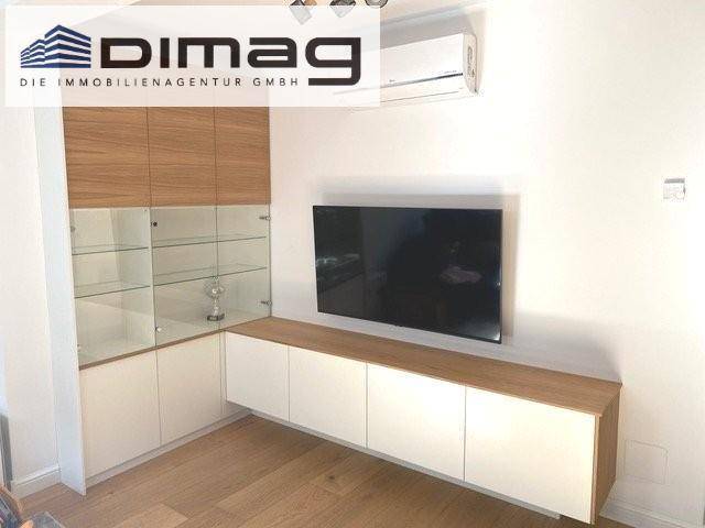Wohnbereich mit wandmontiertem Fernseher, eleganten Einbauschränken und Klimaanlage für Komfort.
