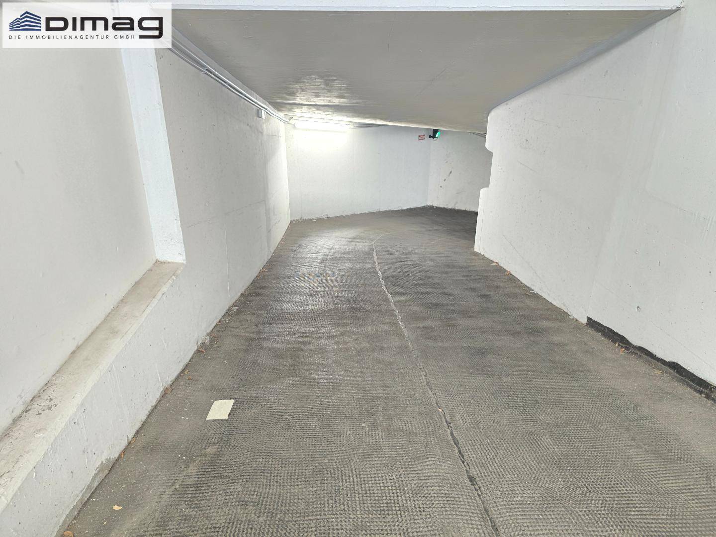 Zufahrtsrampe zur Tiefgarage mit Betonwänden und rutschfestem Bodenbelag.
