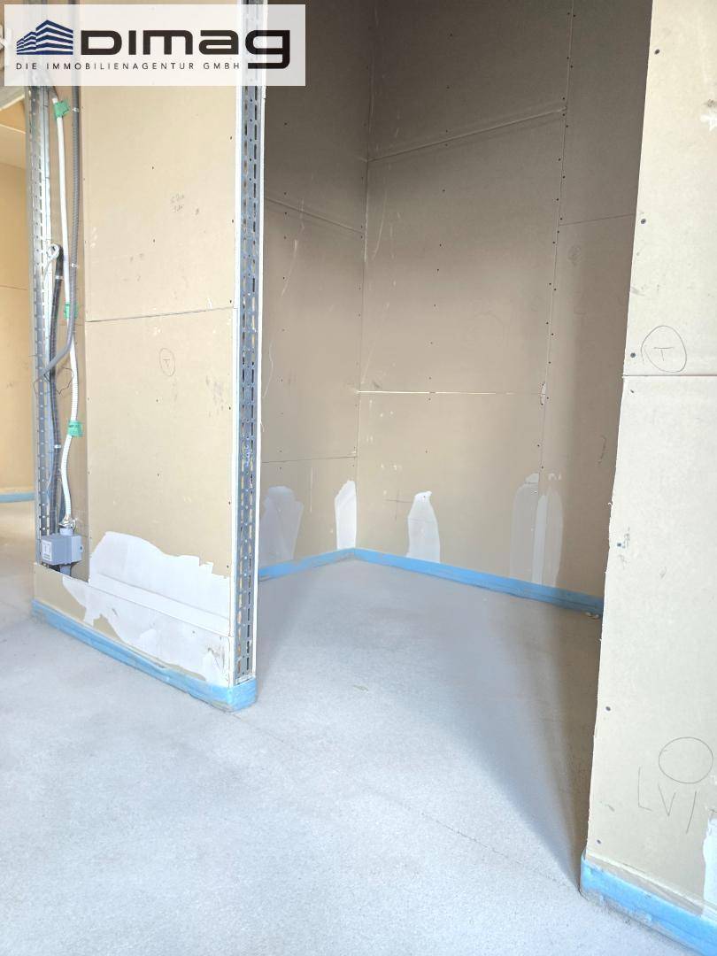 Rohbau eines Flurbereichs mit sichtbaren Installationen und vorbereiteten Wänden.