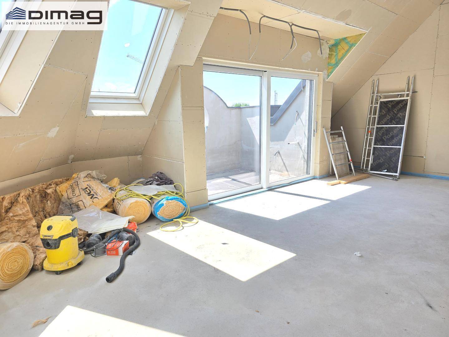 Helles Dachgeschosszimmer im Rohbau mit Schrägen, Dachfenstern und Zugang zu einem Außenbereich.