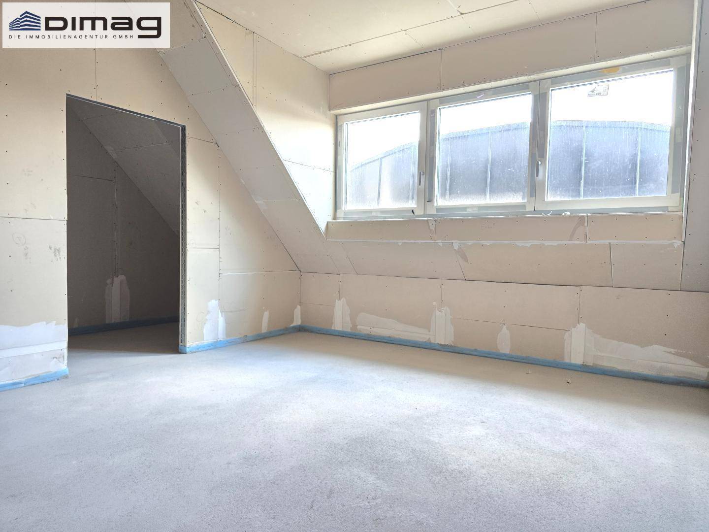 Unfertiger Raum im Dachgeschoss mit Schrägen und Fenstern, bereit für den Innenausbau.