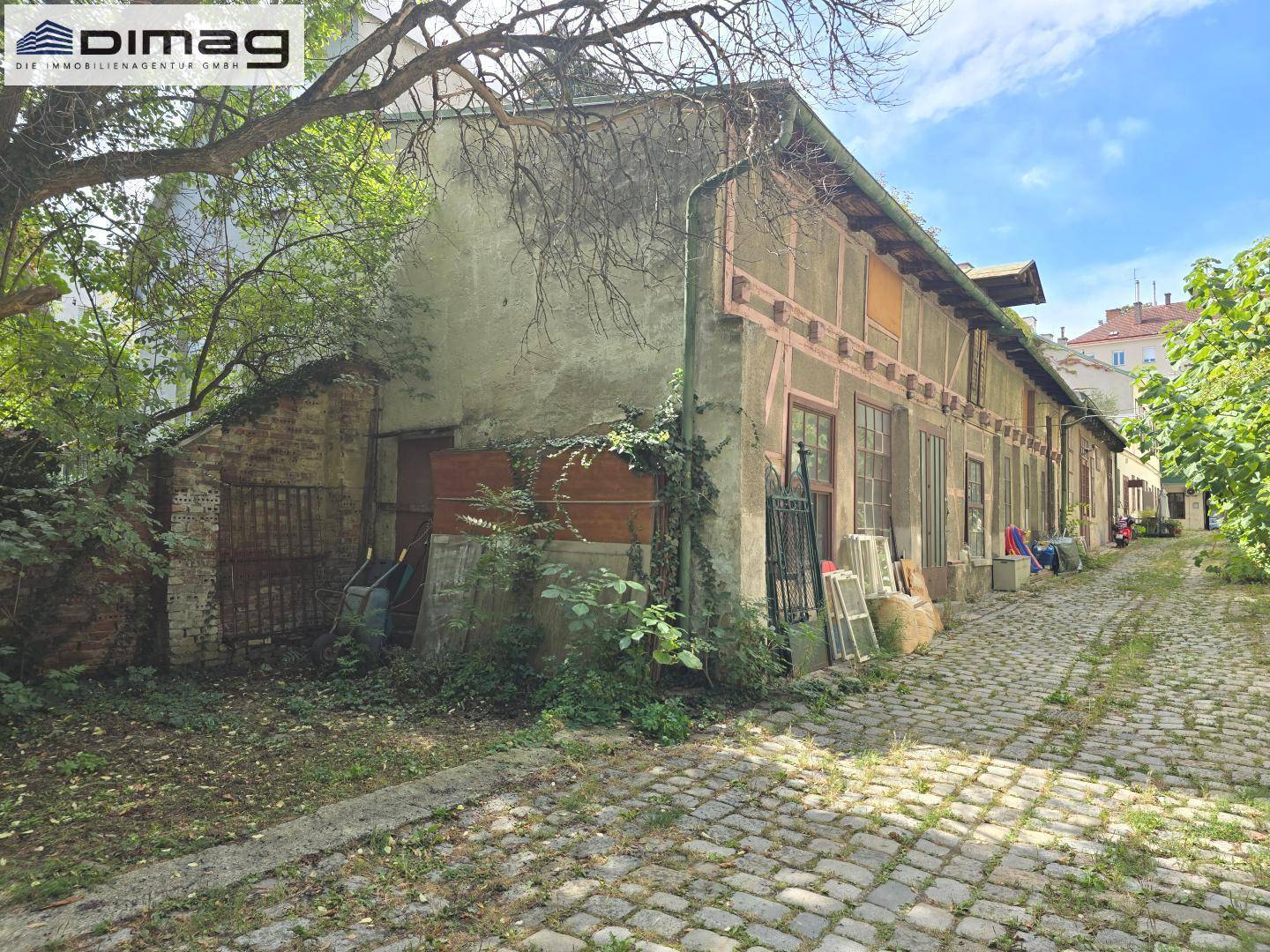 Alte Gebäudefassade mit Fachwerkdetails und bewachsenem Kopfsteinpflasterweg.