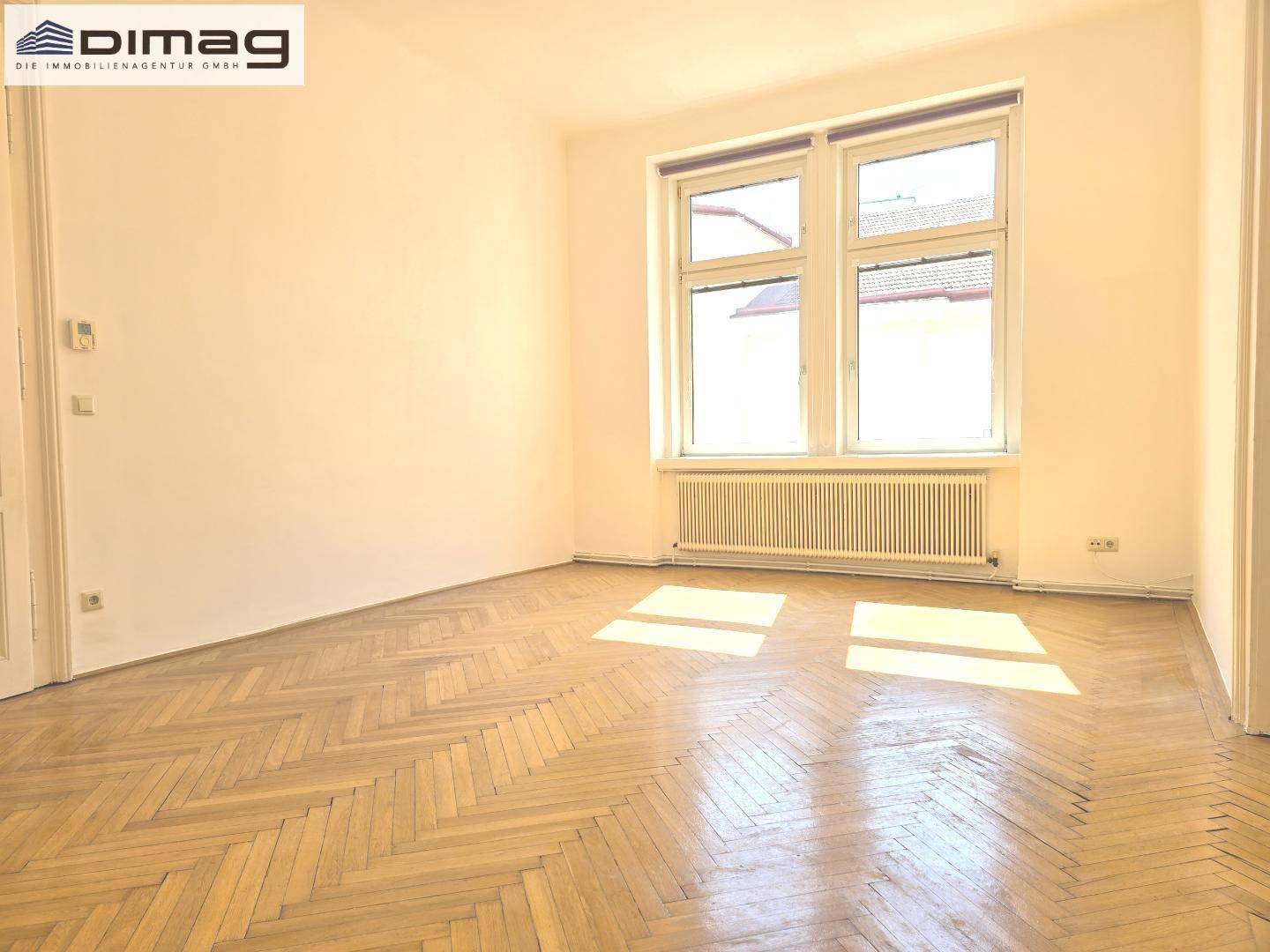 Geräumiges Zimmer mit klassischem Fischgrätparkett und heller Atmosphäre.