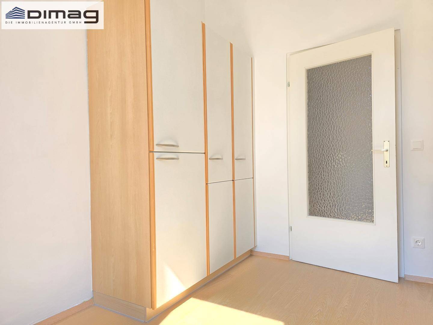 Praktische Einbauschränke mit Holzrahmen und einer Tür mit Glaseinsatz.
