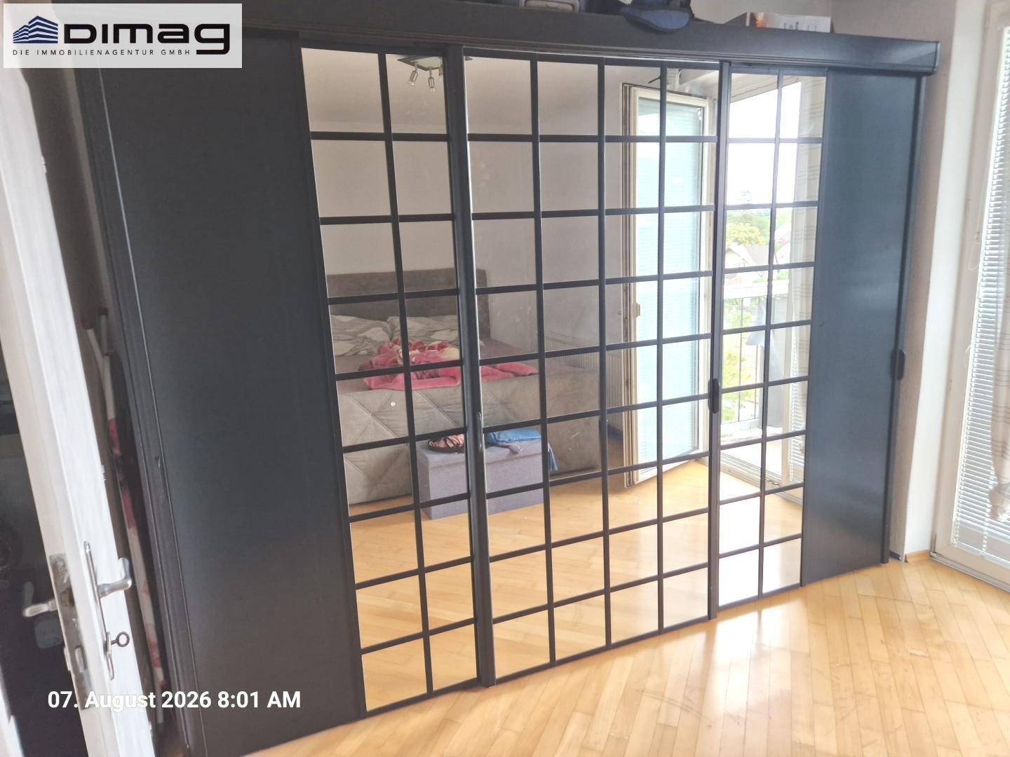Geräumiges Schlafzimmer mit Holzboden und einem Schiebetürenschrank, der den Raum optisch vergrößert.