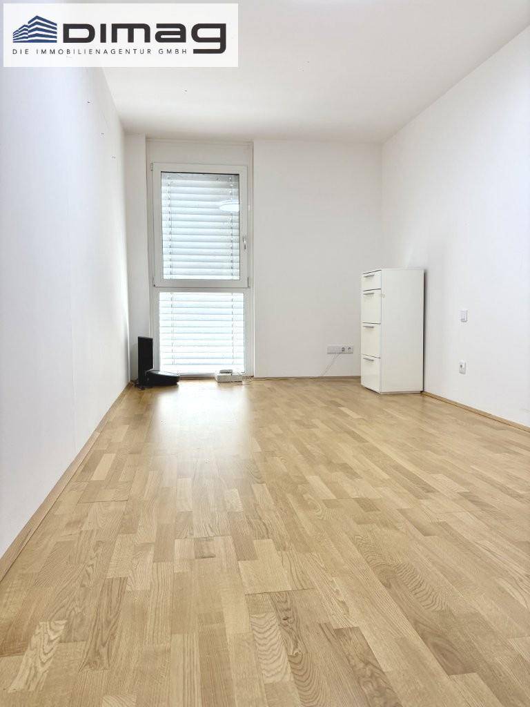 Helles, leeres Zimmer mit Parkettboden und großem Fenster, ideal als Schlafzimmer oder Büro.