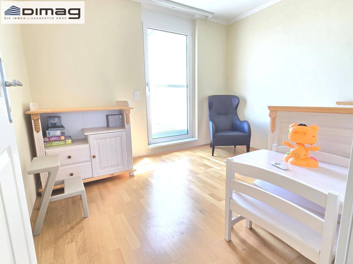 Kinderzimmer mit Parkettboden, hellem Mobiliar und Zugang zu einem Balkon oder Terrasse.
