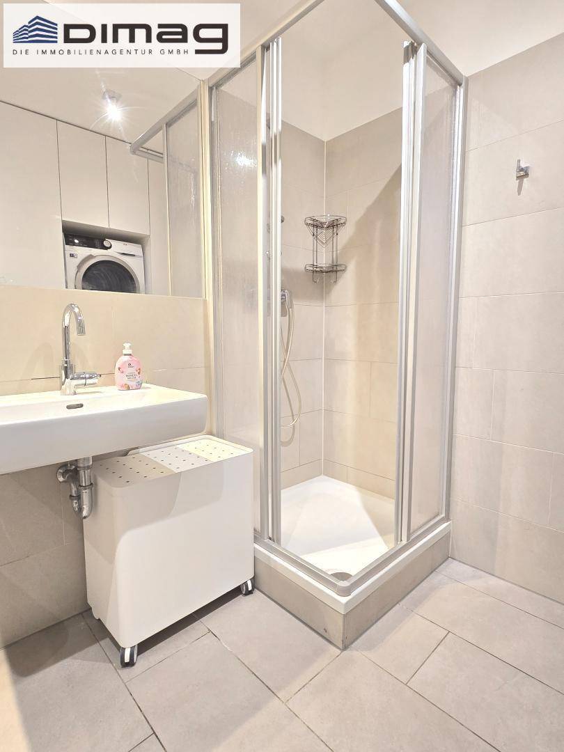 Modernes Badezimmer mit Duschkabine, Waschbecken und Waschmaschine.