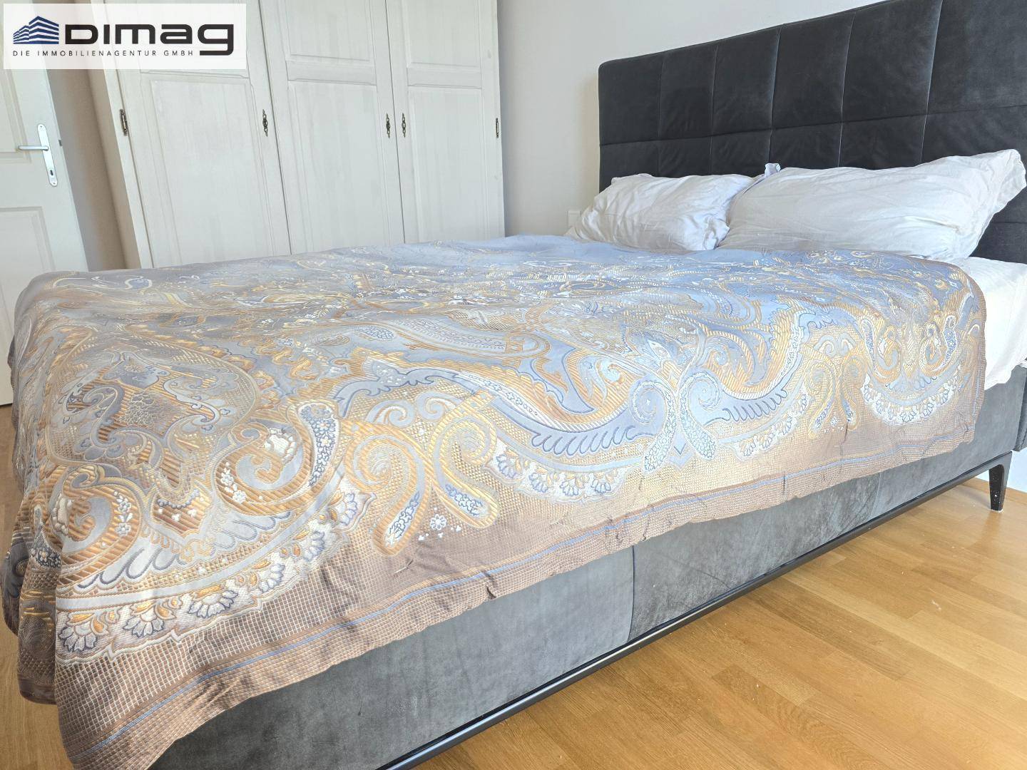 Komfortables Schlafzimmer mit großem Bett, Parkettboden und dekorativer Tagesdecke.