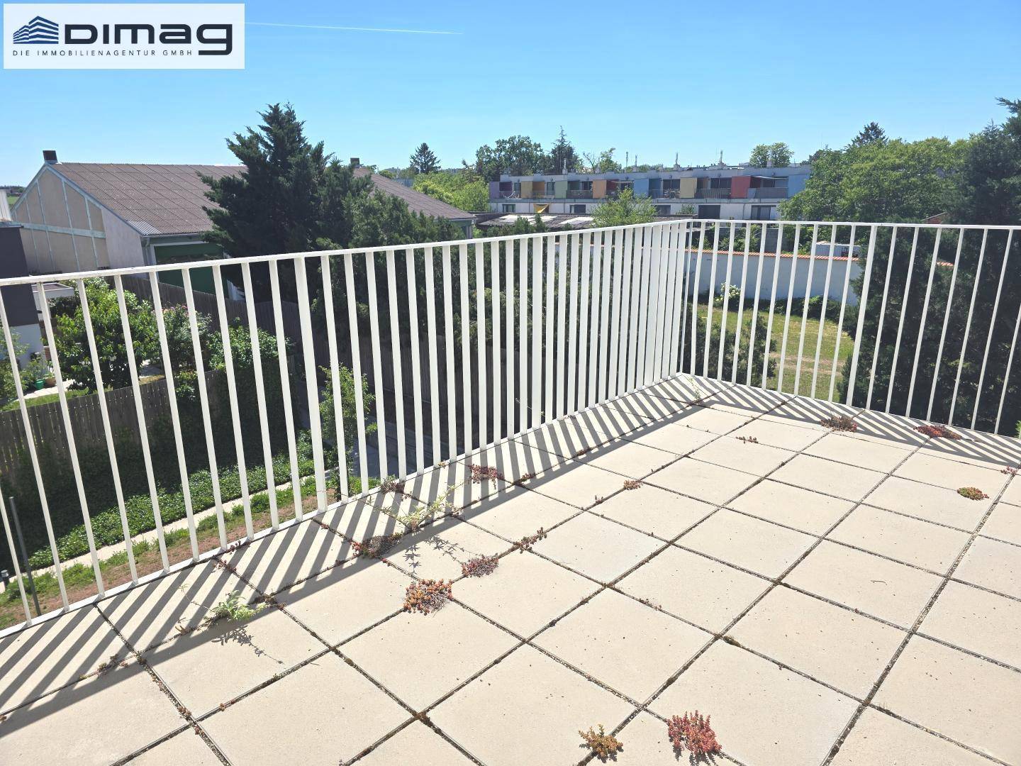 Weitläufige Dachterrasse mit Fliesen und weitem Blick über die grüne Umgebung.