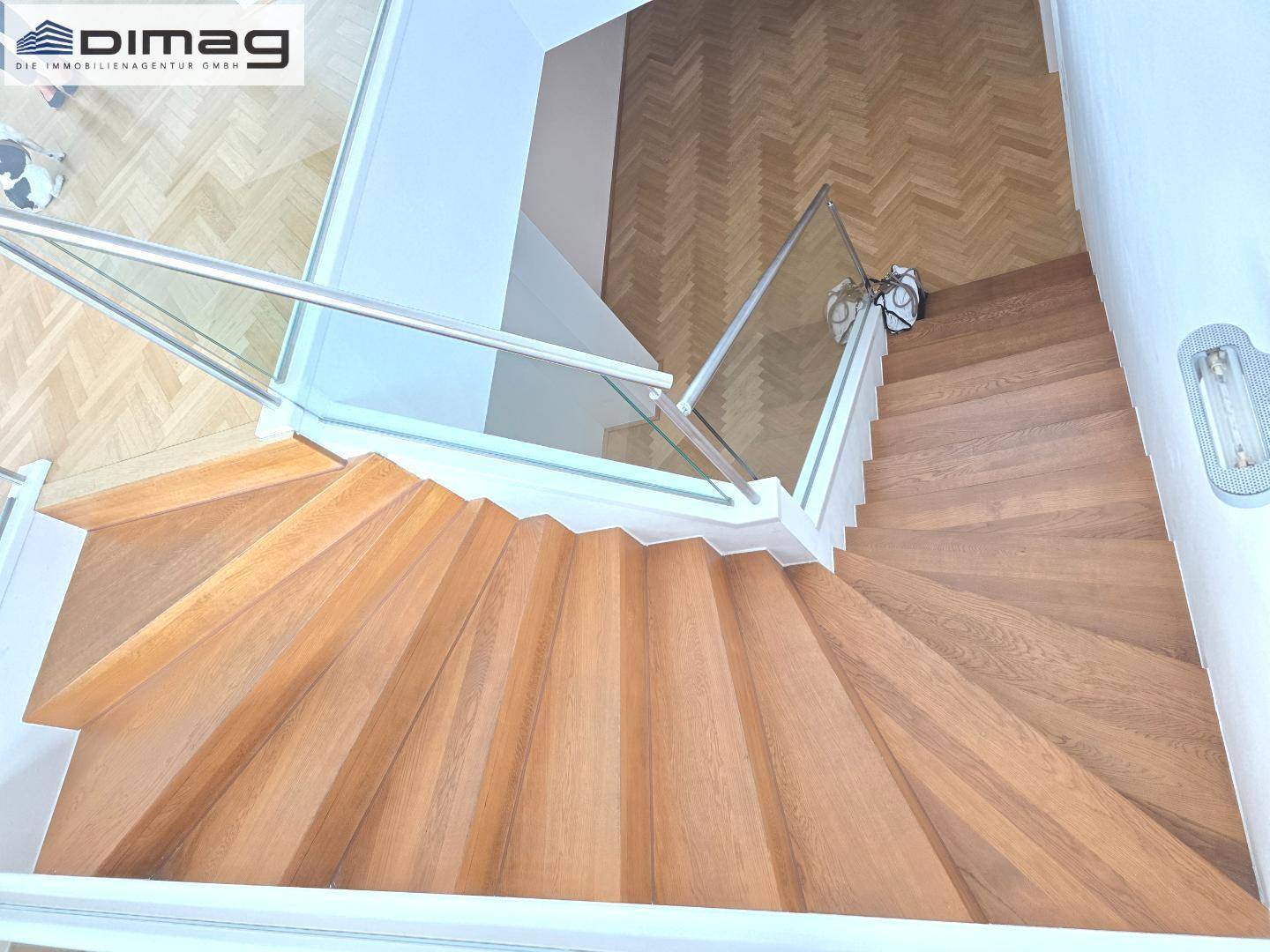 Elegante Holztreppe mit Glasgeländer, die verschiedene Ebenen der Wohnung verbindet.