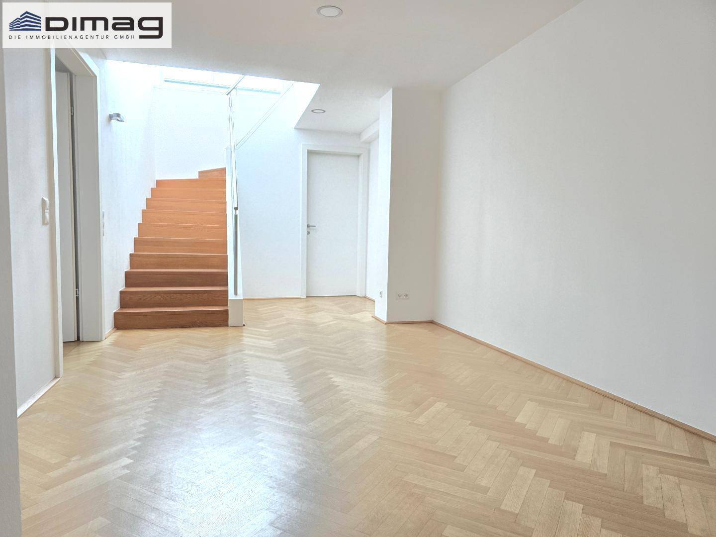 Geräumiger Flur mit Fischgrätparkett und einer offenen Holztreppe, die in die obere Etage führt.