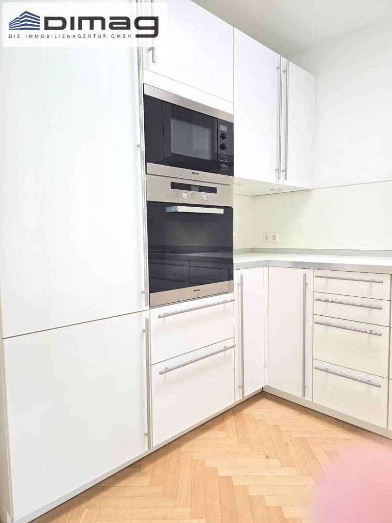 Weiße Einbauküche mit integriertem Backofen und Mikrowelle von Miele, bietet viel Stauraum.