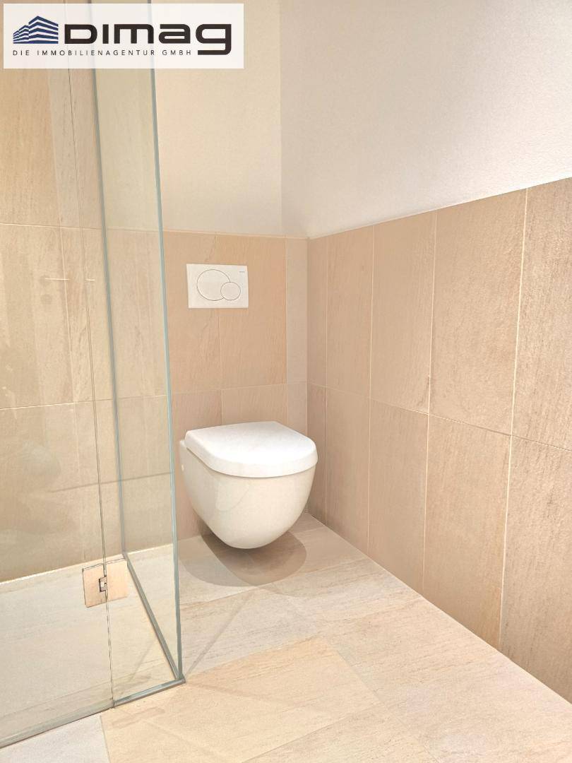 Modernes Badezimmer mit wandhängendem WC und begehbarer Dusche, in hellen Beigetönen gefliest.