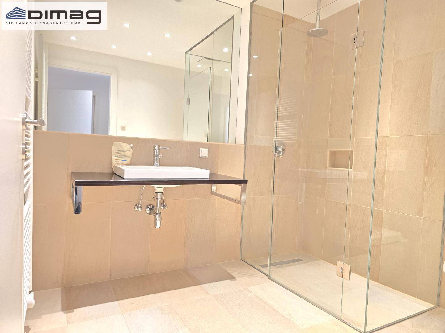 Modernes Badezimmer mit Einzelwaschbecken, großer begehbarer Dusche und beheiztem Handtuchhalter.