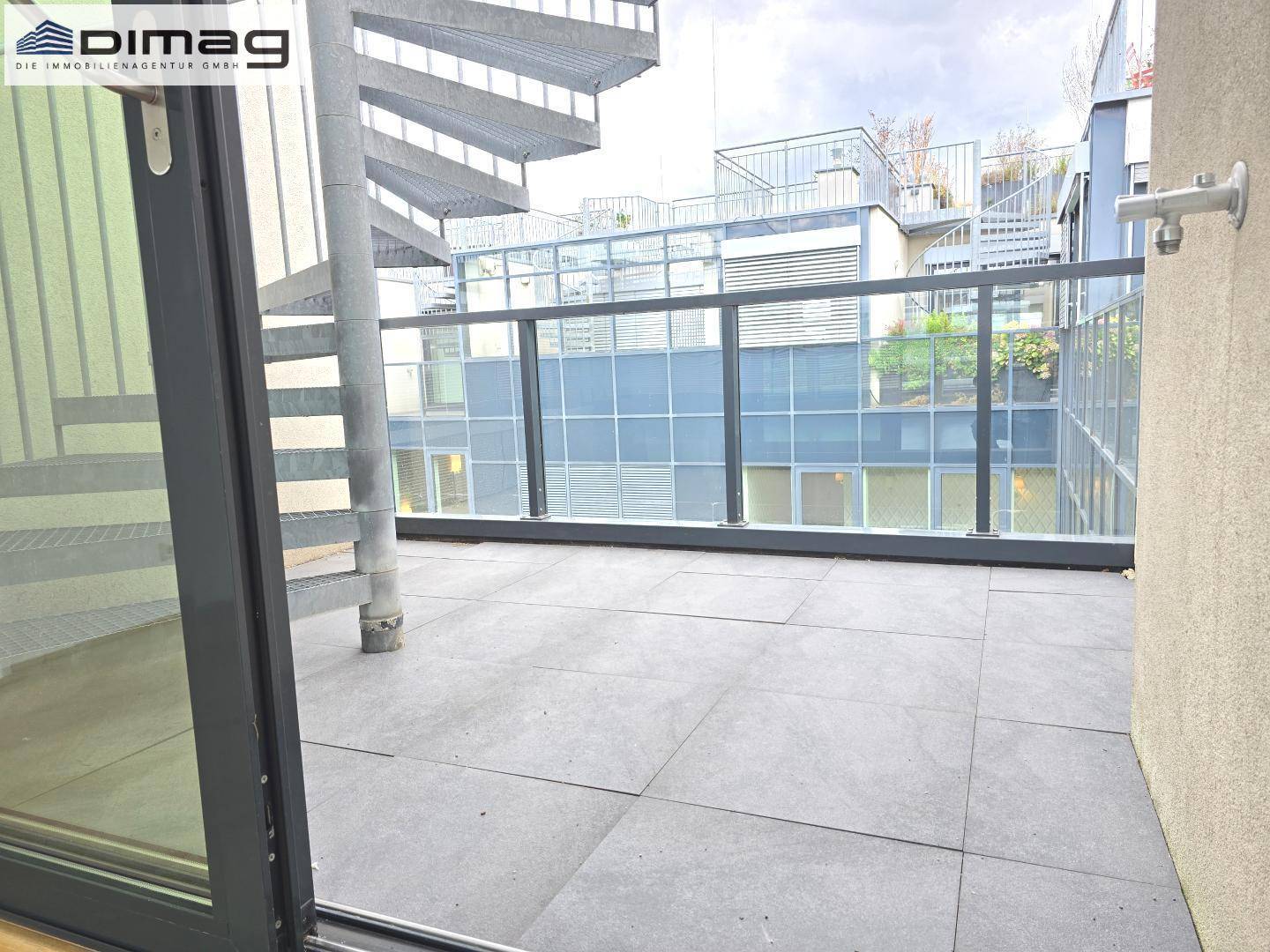 Geräumige Terrasse mit Fliesenboden und einer Wendeltreppe, die zu weiteren Ebenen führt.