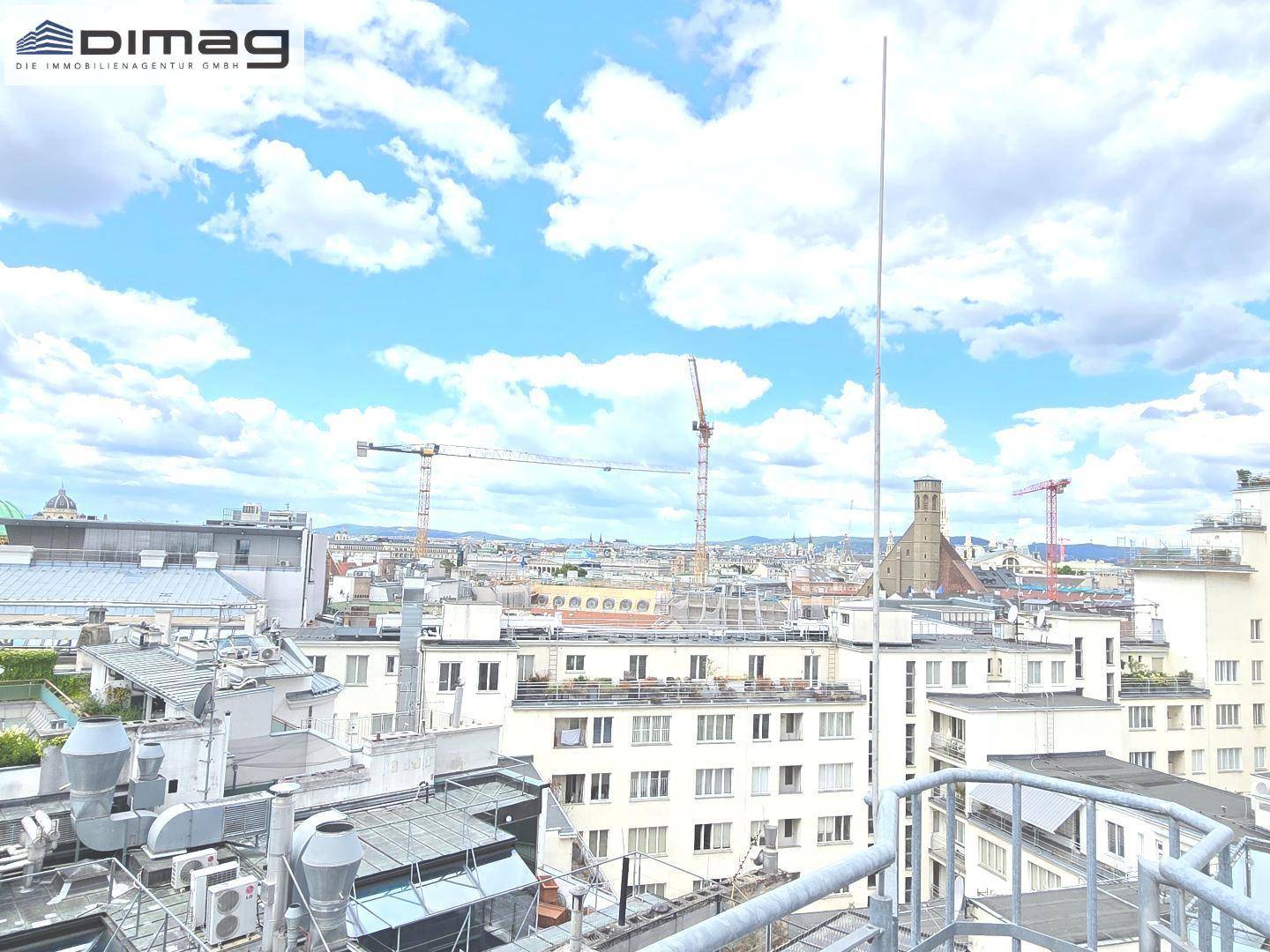 Panoramablick über die Stadt mit zahlreichen Gebäuden und Kränen unter blauem Himmel.