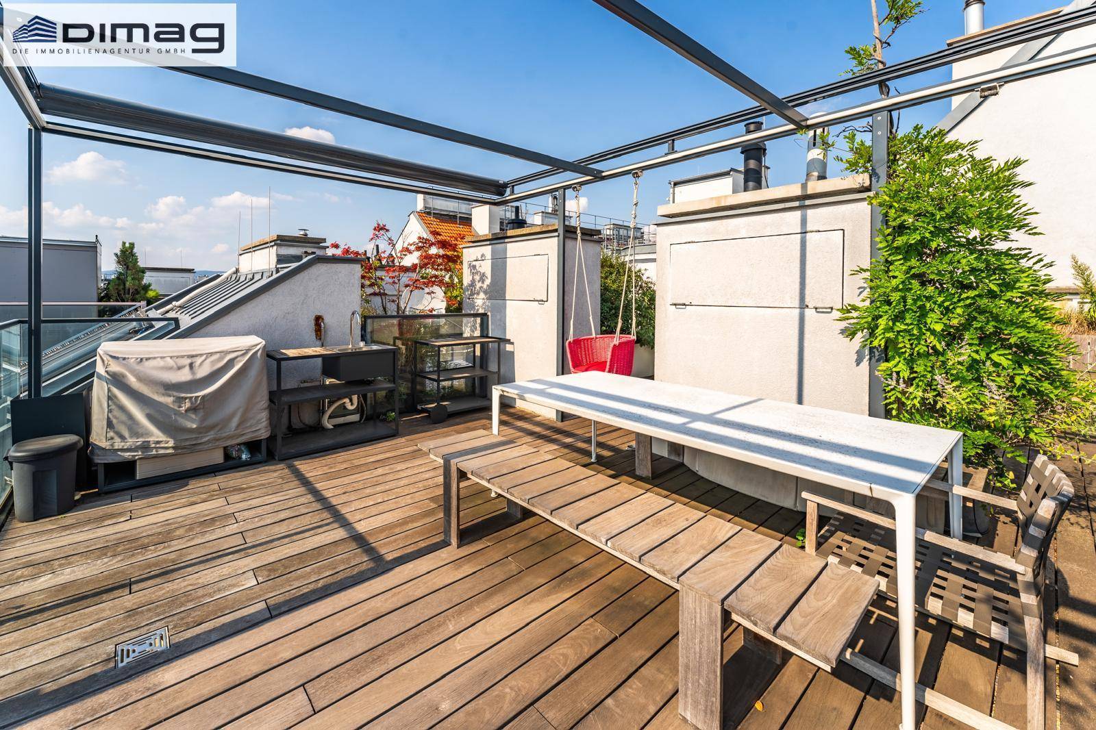 Geräumige Dachterrasse mit Essbereich, Pergola und weitem Blick über die Stadt unter blauem Himmel.