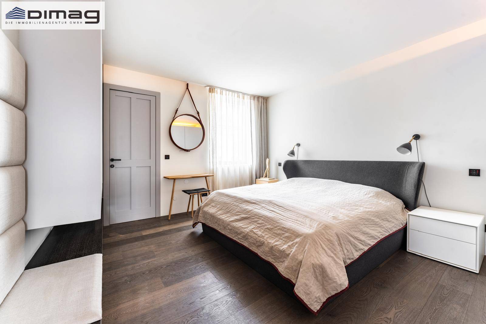 Modernes Schlafzimmer mit dunklem Holzboden, minimalistischer Einrichtung und indirekter Beleuchtung für eine gemütliche Atmosphäre.