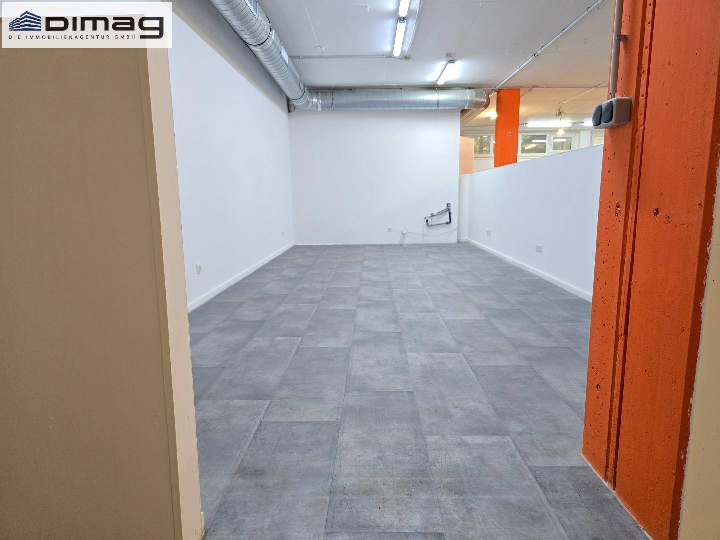 Separater Raum mit modernen grauen Fliesen auf dem Boden und weißen Wänden, ideal als Büro.