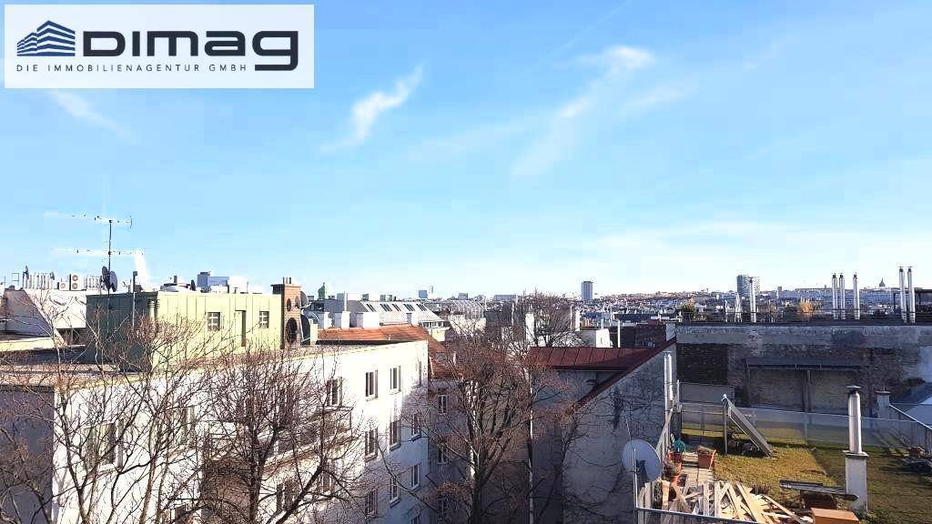 Weitläufiger Blick über die Dächer der Stadt unter blauem Himmel.