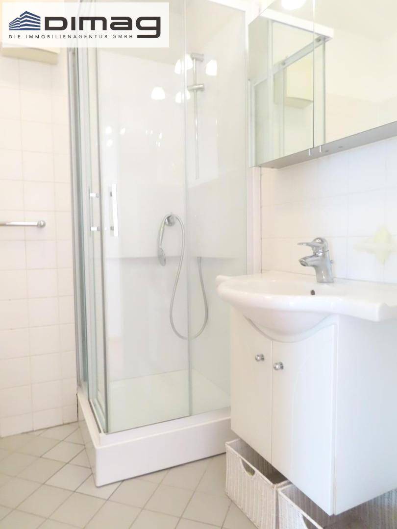 Modernes Badezimmer mit Duschkabine, Waschbecken und Spiegelschrank.