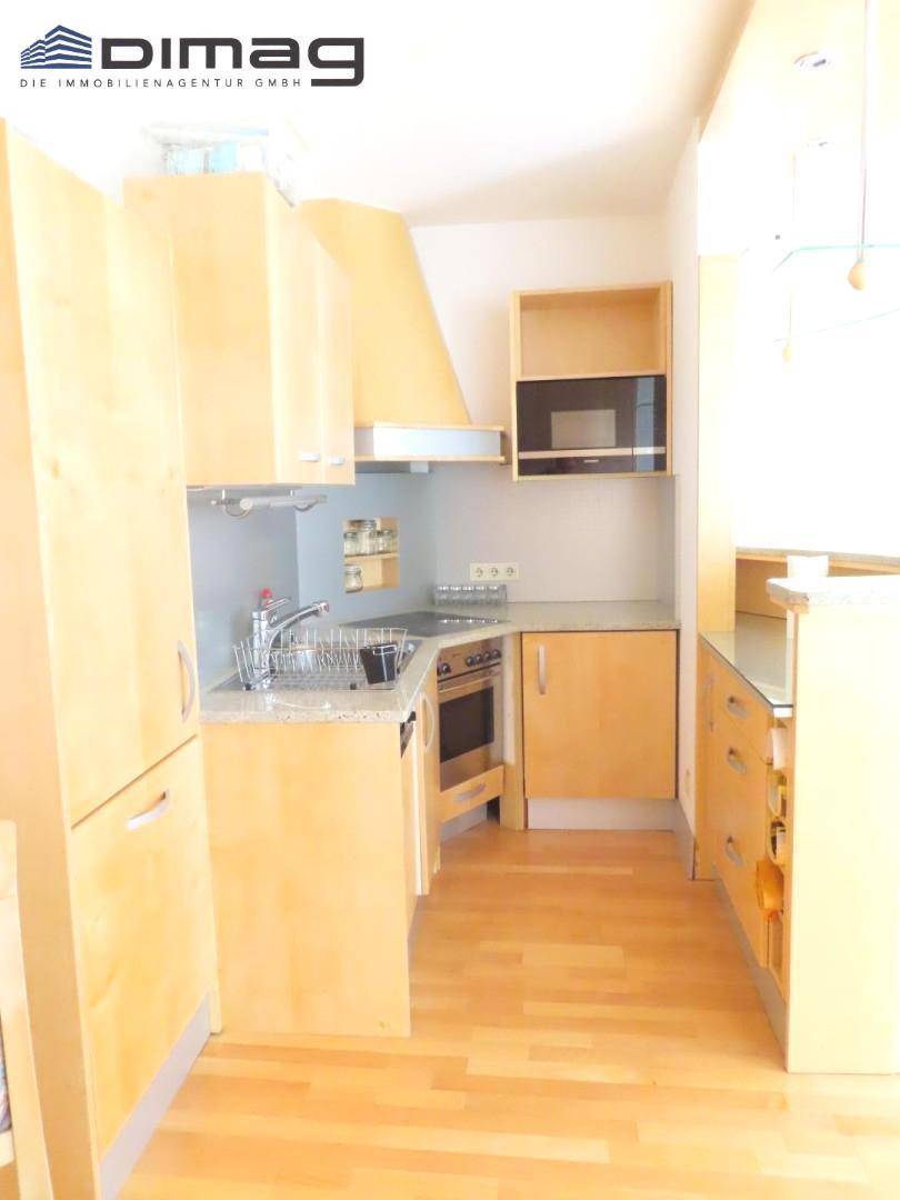 Funktionale Einbauküche mit hellen Holzfronten, integriertem Backofen und Mikrowelle.