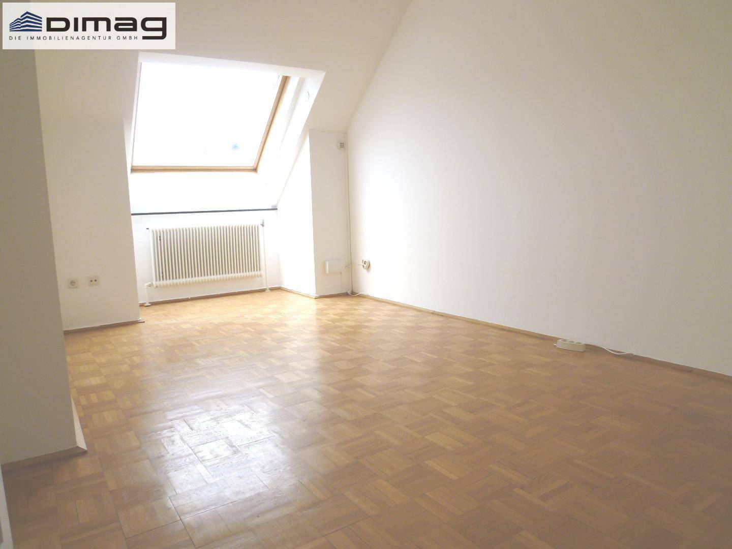 Heller Raum mit Dachfenster, Heizkörper und klassischem Parkettboden.