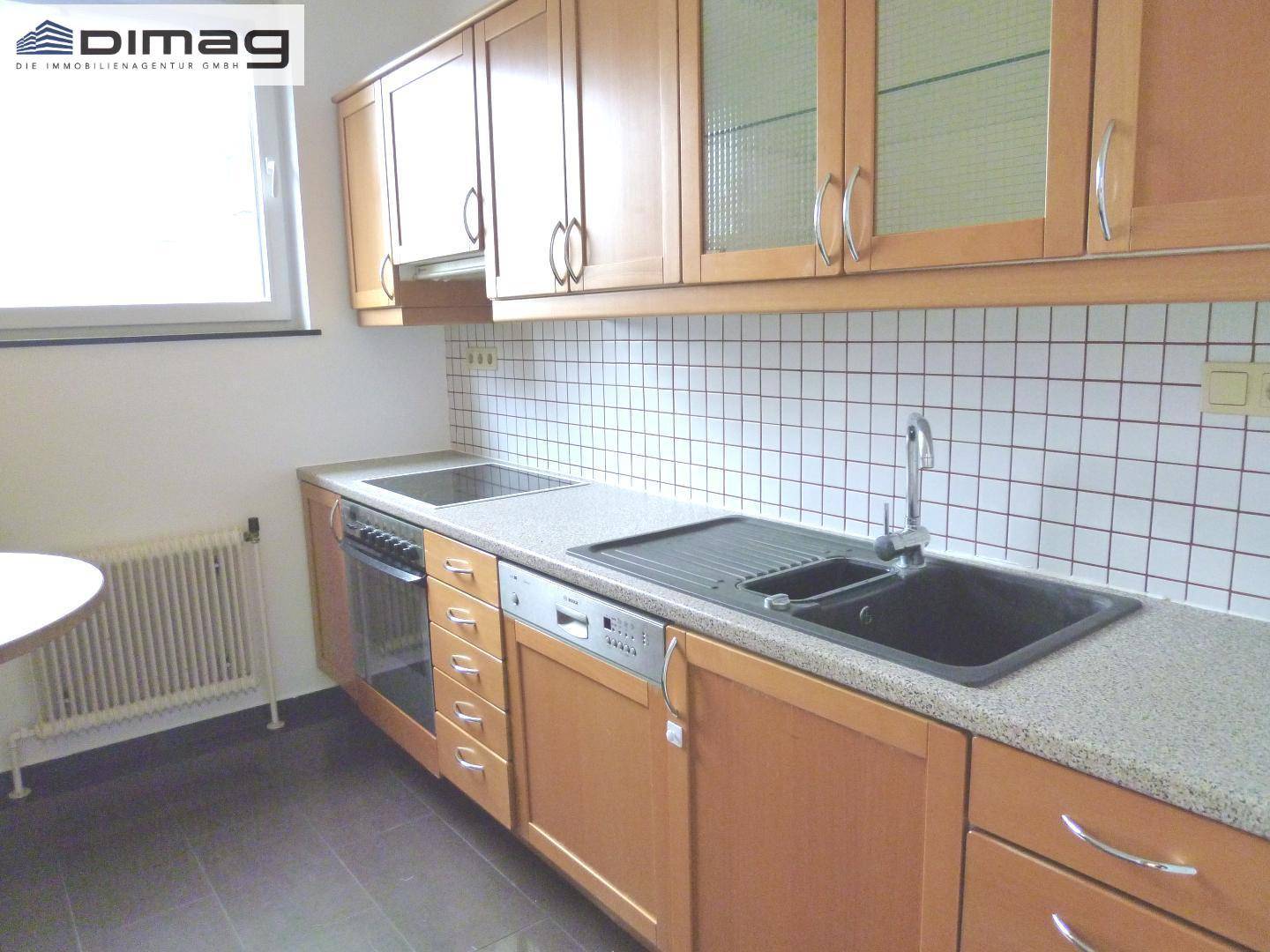 Funktionale Küche mit Holzschränken, Fliesenrückwand und integrierten Geräten.