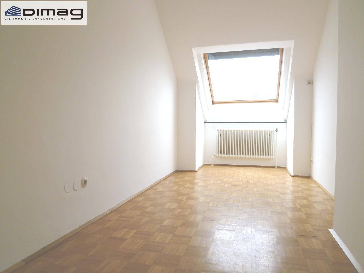 Lichtdurchflutetes Zimmer mit Dachfenster, Heizkörper und Parkettboden.